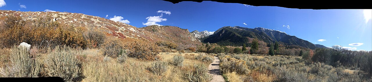 Gravel trail leading through sagebrush and scrub oak toward the snow-dusted granite peaks of Bells Canyon